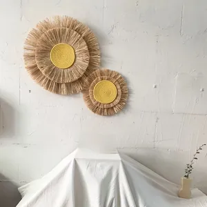 Detail of Nordic raffia wall decor with natural fiber fringe and yellow woven center