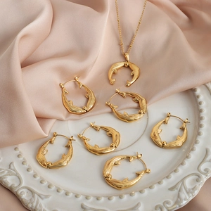 Golden whale bead necklace and earrings set on elegant white relief plate and silk
