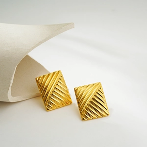Macro view of gold 18K rectangle earrings with unique diagonal striped texture detail