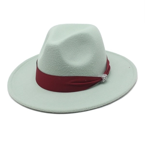 Detail of mint green wool fedora featuring a deep red silk band and rhinestone buckle