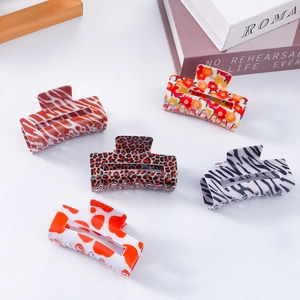 Set of five stylish rectangular hair claw clips with various trendy patterns on a desk
