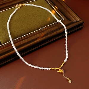Detailed view of pearl necklace with gold gourd and tassel charms on vintage leather base