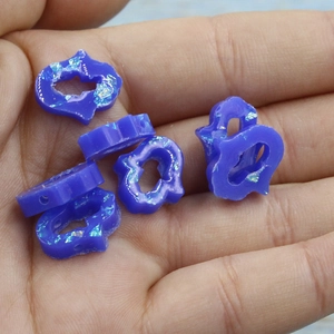 Macro view of blue opal-style hamsa resin beads with iridescent glitter for DIY jewelry