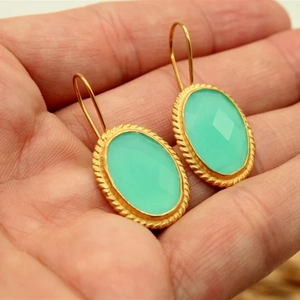 Detailed macro view of vintage gold hoop earrings with oval mint green faceted crystals