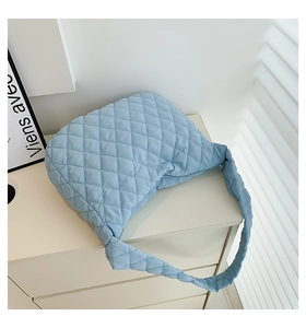 Detailed macro view of the blue quilted rhombic pattern on a soft puffer shoulder bag