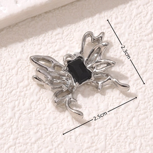 Macro view of silver butterfly charm with black gem and 2.5cm size markings