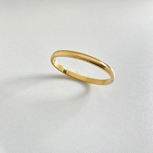 Detail showing high-polished golden stainless steel bangle with a minimalist clasp design