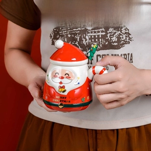 Detail view of red ceramic Santa mug with lid and spoon being held by a person