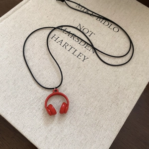 Detail of creative red headphone pendant with black cord on beige linen book