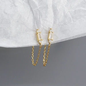 Close-up of gold chain earrings with rectangular and round cubic zirconia stones