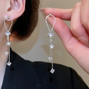 Gros plan de boucles d'oreilles pompons en argent avec quatre zircons de coupe carrée