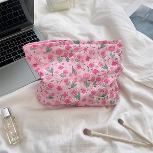 Pink floral quilted cosmetic bag with sozakka tag on a cozy white bed linen setting