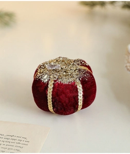 Close-up of a burgundy velvet pumpkin ornament with thick gold sequins and glitter bands
