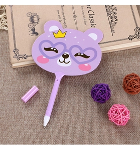 Detailed close-up of a purple bear-shaped fan pen on a rustic book and mat background