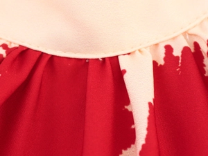 Gros plan détaillé du tissu plissé rouge avec imprimé abstrait de cocotiers beige