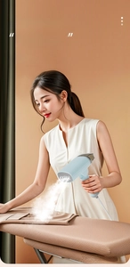 Close-up of portable blue handheld steamer emitting strong steam on brown fabric surface