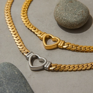 Titanium steel heart necklaces in gold and two-tone finishes on grey stone texture