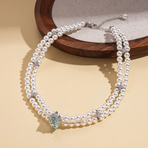 Detail of elegant double-layered pearl necklace with large light blue gemstone pendant