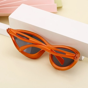 Detail of orange streamlined sports sunglasses frame with grey lenses on display base