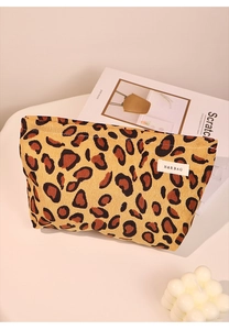 Detail view of leopard print corduroy makeup bag with woven brand label and zip closure