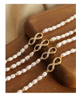 Close-up of freshwater pearls with gold infinity pendant and micro-set cubic zirconia