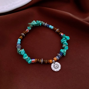 Gros plan du bracelet en perles bohème avec turquoise, oeil de tigre et pendentif soleil