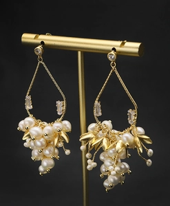 Gros plan détaillé des boucles d'oreilles perles naturelles et feuilles dorées
