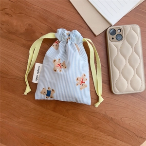Detail view of blue striped cotton drawstring bag with cartoon bear pattern on wood table