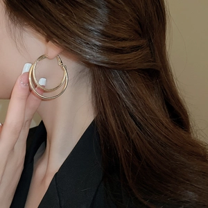 Close-up of a double-layered gold hoop earring with twisted texture worn by a model