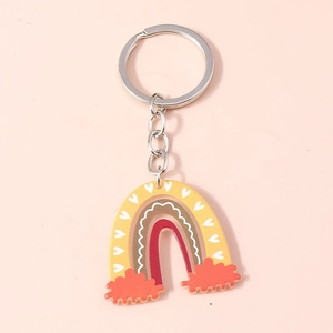Close-up of a colorful acrylic rainbow keychain with white hearts on a pink background