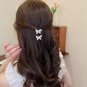 Close-up of diamond and pearl butterfly hair clips worn on a half-up hairstyle