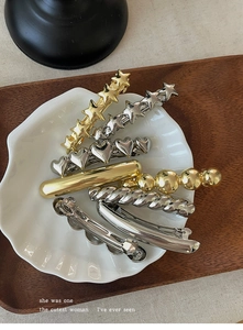 Macro shot of assorted gold and silver geometric metal spring hair clips in shell tray