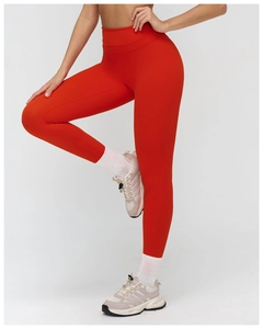 Detailed macro view of high-waist yoga pants in orange-red matte fabric with compression