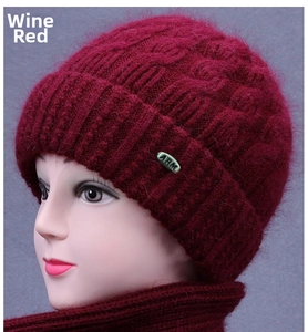 Detail of wine red knitted hat with plush texture and metallic brand tag for elderly women
