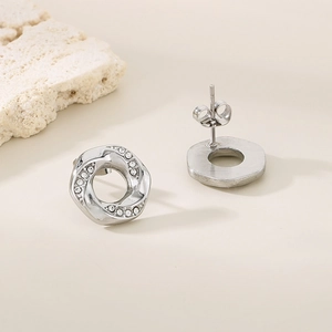 Silver twisted round stud earrings with pave crystals on white stone minimalist background
