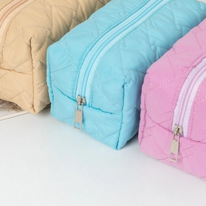 Detailed view of quilted cosmetic bags in khaki, blue and pink with metal zippers