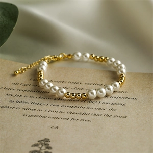 Detail of elegant white pearl and gold bead bracelet on a vintage script background