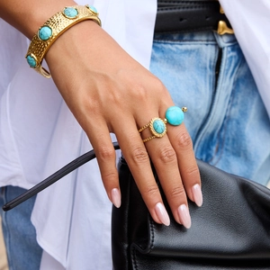 Detail of 18K gold-plated hammered bangle and turquoise ring on a female model