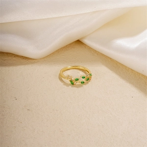 Elegant gold olive leaf open ring with green zircon stones on a silk background