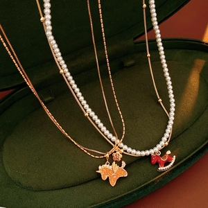 Detail showing enamel horse pendants and layered pearl necklaces in a velvet jewelry box