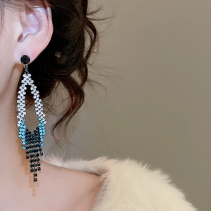 Détail boucles d'oreilles losange avec pompon dégradé bleu porté par un mannequin