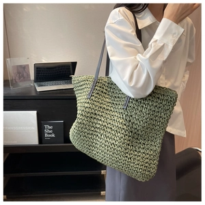 Detail of green woven straw tote bag with leather handle shown in a minimalist home setting