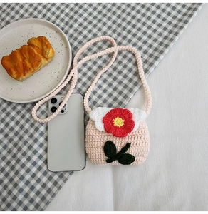 Handmade crochet mini crossbody bag with flower detail and smartphone for scale