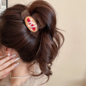 Detailed view of the hot dog plush hair claw clip worn on wavy dark hair for styling
