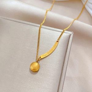 Detailed macro view of gold-plated smiley face and engraved bar pendant necklace