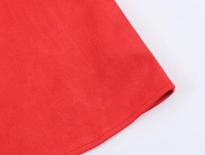Détail de la texture en daim rouge et des coutures précises sur l'ourlet du vêtement