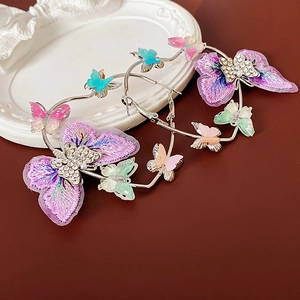 Détail de créoles avec papillons en broderie violette et accents colorés en résine