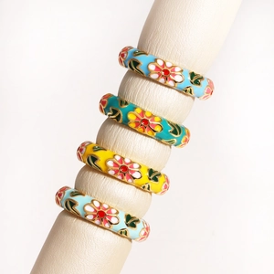 Floral enamel stacking rings in pastel blue green and yellow on a cream display stand