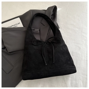 Detail showing the black suede texture and decorative knot on this stylish hobo bag