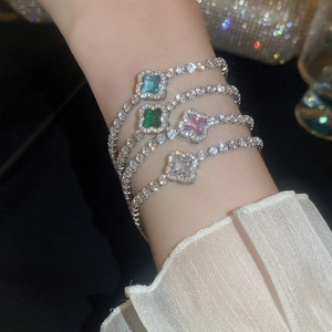 Detail of four colorful zircon clover bracelets stacked on a wrist with silver finish